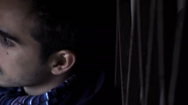 Vážnou strašidelný mladý muž v soumraku se dívá na kameru — Stock video