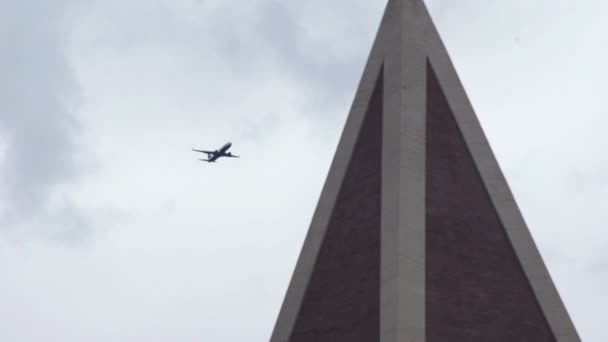 Trafikflygplan flyger över staden nära kyrkan — Stockvideo