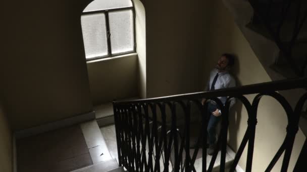 Worried business man leaning against the wall in the shadows — Stock Video