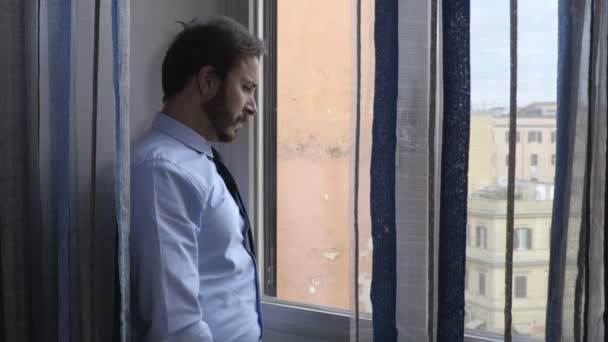 Junger depressiver Geschäftsmann blickt aus dem Fenster seines Büros — Stockvideo