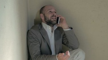Yerdeki telefonu ağlayarak konuşuyor çömelme adam