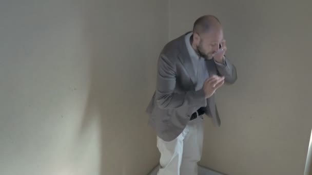 Bald man on the stairs receives bad news on the phone — Stock Video