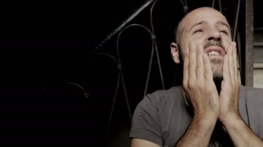 Yalnız yüzünü elleri ile dokunarak ağlayan adam