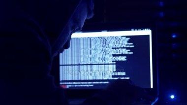 kapüşonlu genç hacker bir bilgisayar ihlal edilmesi sırasında bir sigara yakıyor