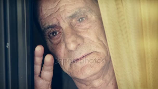 Старик смотрит в окно — стоковое видео