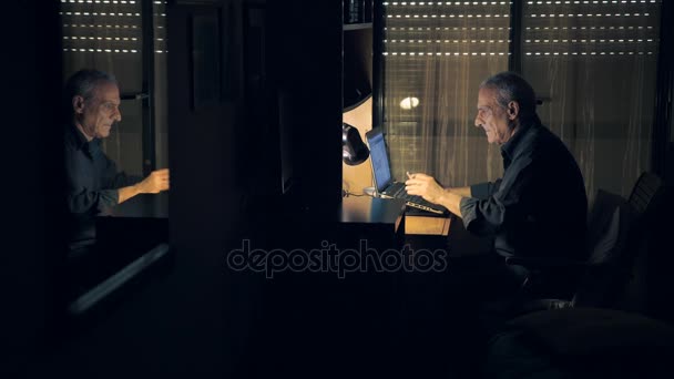 Курение старик печатает на ноутбуке — стоковое видео