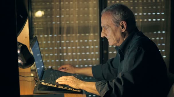 Geconcentreerde oude man te typen op laptop — Stockvideo