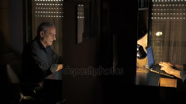 Oude man terwijl roken en typen op zijn computer — Stockvideo