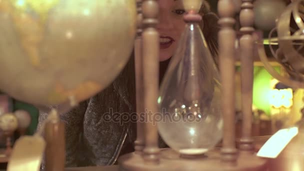 Beautiful girl looks an antique hourglass — Stock Video