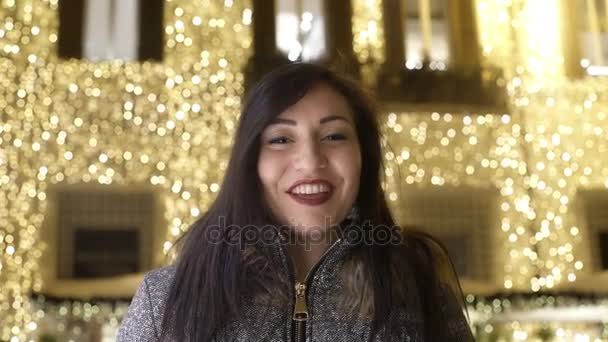 Šťastná žena se usmívá s vánoční osvětlení za — Stock video