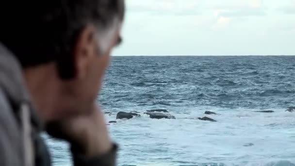 Чоловік з п'ятдесяти спостерігає штормове море — стокове відео