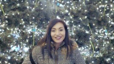 Işıklı Noel ağacı yakınındaki gülümseyen genç kadın