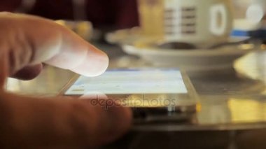 Adamın elini bir smartphone ekranında kahvaltı sırasında çalışır.