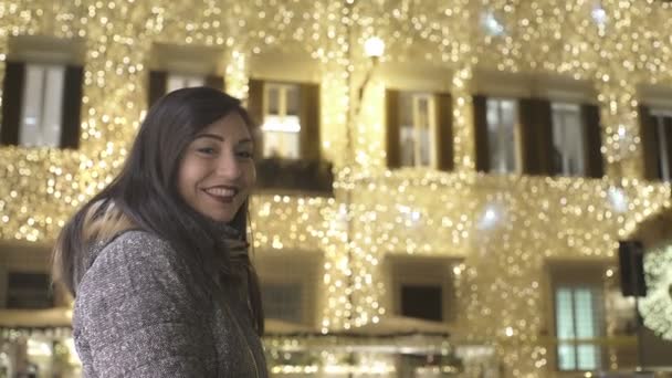 Mulher feliz sorrindo para a câmera com palácio iluminado no fundo — Vídeo de Stock