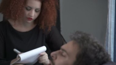 Kızıl saçlı genç psikolog onu hasta için dinleme notlar alır