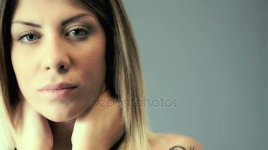 Seksi kadın endişeyle kameraya bakarak boynuna dokunuyor