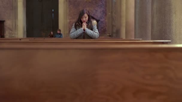 Печальная молодая женщина отчаянно молится в церкви — стоковое видео