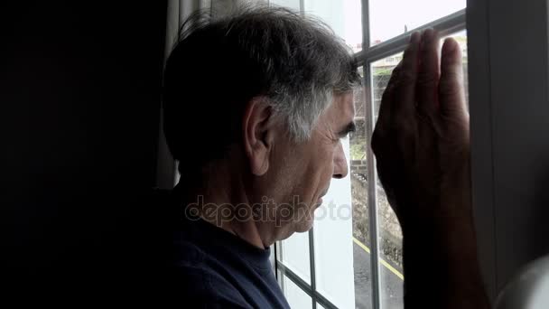 Reifer Mann in der Dämmerung blickt aus dem Fenster — Stockvideo