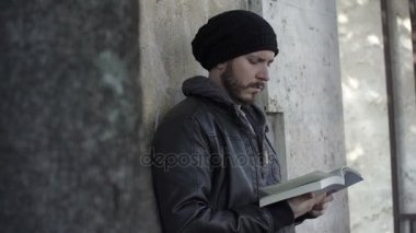 Öğrenci mermer duvara oturan bir kitap okur