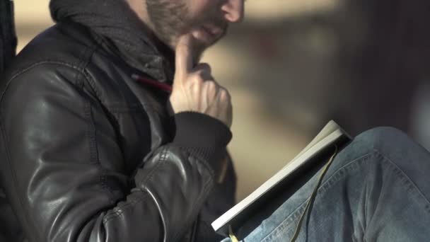 Человек с бородой пишет в своем дневнике — стоковое видео