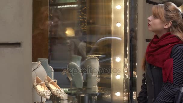 Junge blonde Frau blickt auf die Schaufenster der Straße — Stockvideo