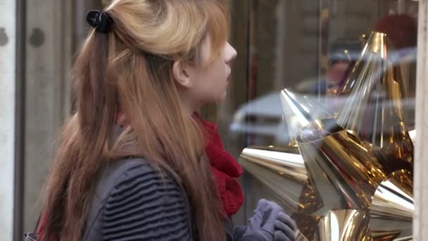 Blonde vrouw stopt voor een venster tijdens het winkelen van Kerstmis — Stockvideo