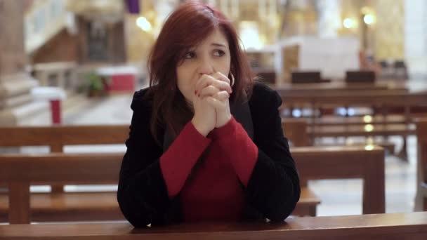 La mujer en la iglesia está haciendo la señal de la cruz mirando a la cámara — Vídeo de stock