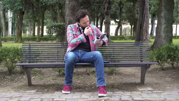 Joven en el parque la intención de leer, recibe un mal mensaje en el teléfono inteligente — Vídeo de stock