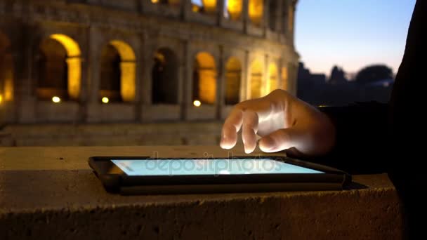 Молодой человек рука использует планшет с фоном Колизей ночью — стоковое видео