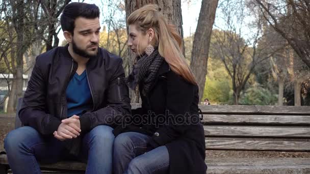 Любящая пара нежно разговаривает и обнимается на скамейке в парке — стоковое видео