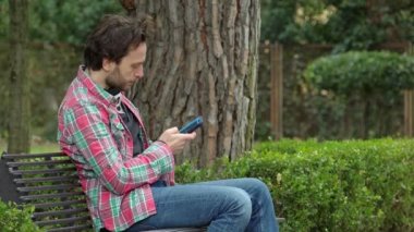 adam onun smartphone cep telefonu ile kötü haber alma bir Bank üzerinde okuma