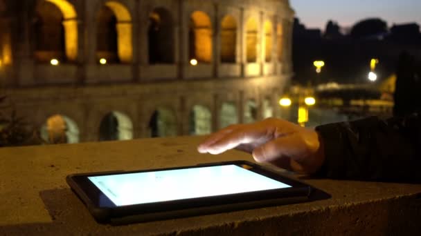 Ο άνθρωπος χέρι χρησιμοποιώντας tablet κλίνει ενάντια σε έναν τοίχο με φόντο το Κολοσσαίο — Αρχείο Βίντεο