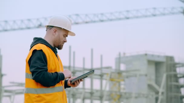 Ung ingenjör i en byggarbetsplats med tabletten — Stockvideo