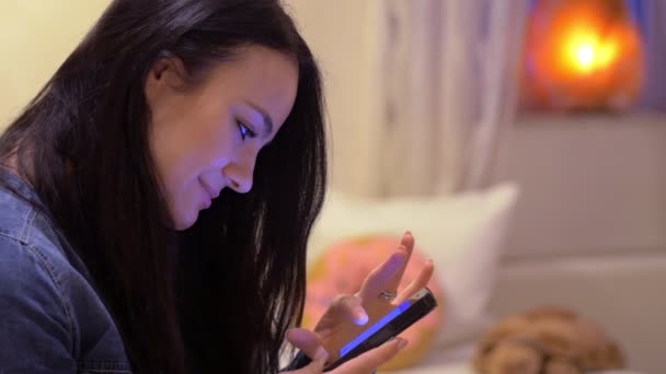 Mujer feliz en casa escribe a su novio con el teléfono celular — Vídeos de Stock