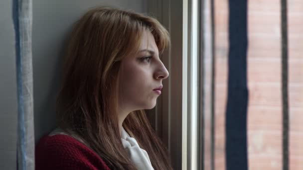 Perfil de mujer rubia, triste y atenta a la ventana — Vídeo de stock