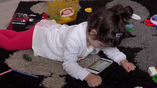 Doce menina no chão jogando com smartphone — Vídeo de Stock