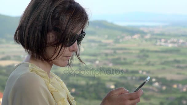 Mujer con gafas de sol grandes para comprobar los mensajes en el teléfono inteligente — Vídeo de stock