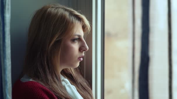 Mujer pensativa, ansiosa, nerviosa mira por la ventana — Vídeos de Stock