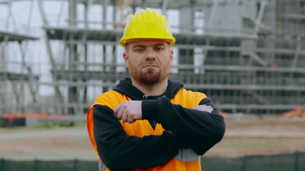 Ernsthafter Bauarbeiter verschränkt die Arme und starrt in die Kamera — Stockvideo