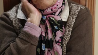 eski büyükanne oturan kameraya bakarak ve gözlerini kapatır