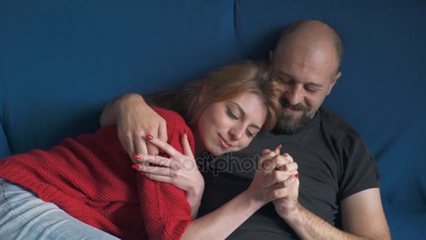 Двое влюбленных, обнявшись на диване, играют руками — стоковое видео