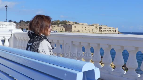 Samotna wdowa, siedząc na ławce patrząc na morze — Wideo stockowe