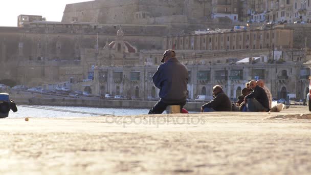 Solnedgång i Malta: fiskare fiske med fiskespön i den port - Valletta, Malta — Stockvideo