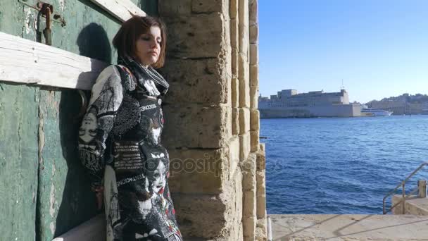 Femme mûre réfléchie appuyé contre une porte près de la mer — Video