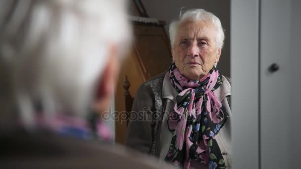 Λυπημένος και καταθλιπτικός ηλικιωμένη γυναίκα στον καθρέφτη αγγίζει τα μαλλιά — Αρχείο Βίντεο