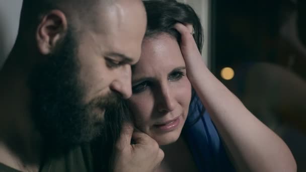 Мужчина утешает отчаявшуюся девушку у окна — стоковое видео