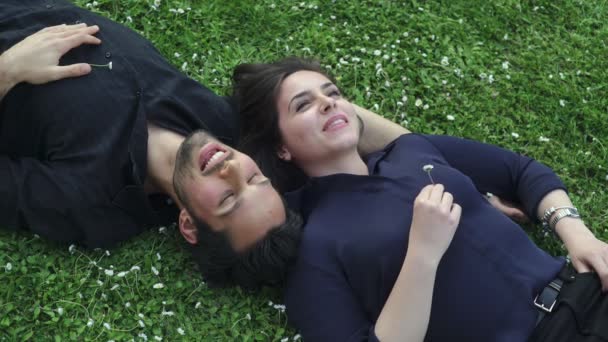 Paar minnaars liggend op het gras chatten teder — Stockvideo