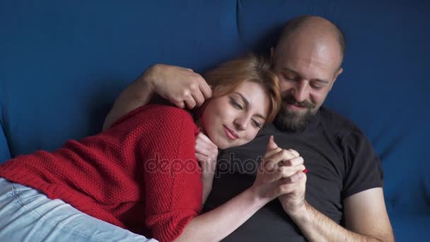 Casal macio no sofá azul está abraçando suavemente — Vídeo de Stock