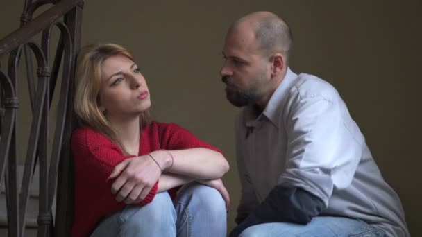 Angry woman sitting on the stairs is reached by the boyfriend comforting her — Stock Video