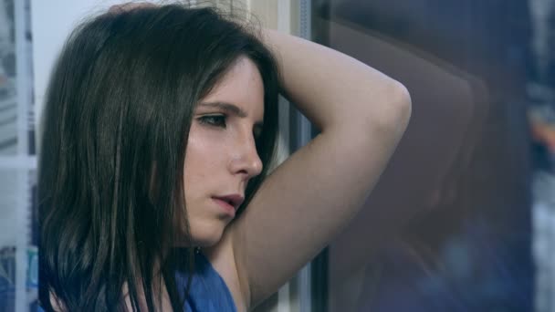 Sad and thoughtful brunette to the window — Stock Video